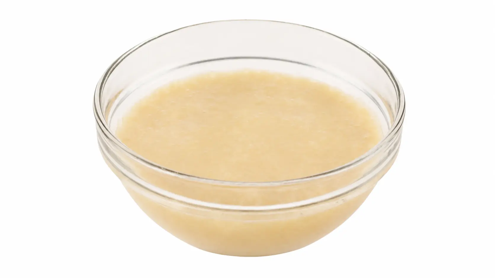 Fresh pale cream-yellow banana puree in a clear glass bowl